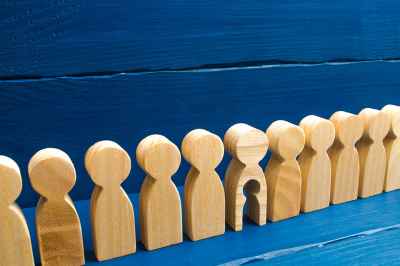 Holzfiguren in einer Reihe, eine hat ein ausgeschnittenes Kind