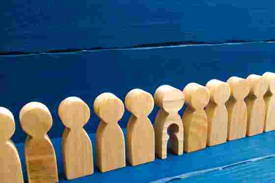 Holzfiguren in einer Reihe, eine hat ein ausgeschnittenes Kind